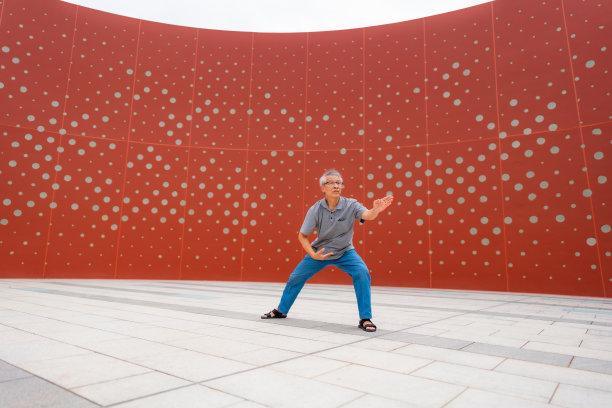 一位老人在红墙的背景下跳舞图片下载