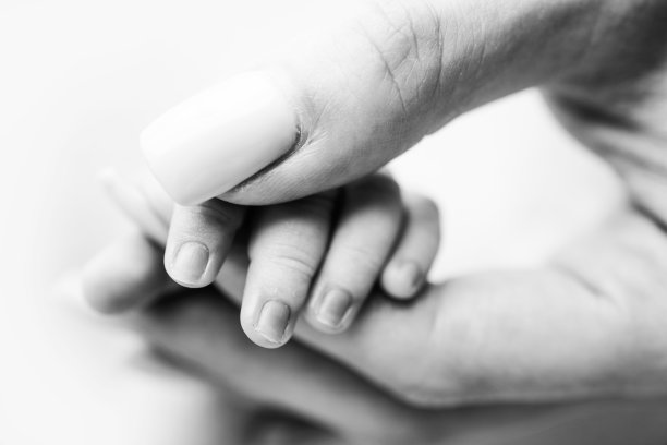 婴儿的小手与母亲的小手指和手臂的特写。新生儿出生后握着父母的手指。母亲和孩子之间的纽带。幸福的家庭的概念。黑色和白色。图片下载