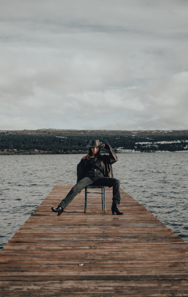 一个多云的日子，牛仔女孩坐在雪地上的马鞍上，整理着她的帽子和皮夹克图片下载