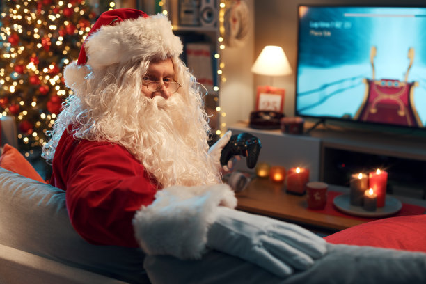 有趣的圣诞老人在家里玩电子游戏图片下载