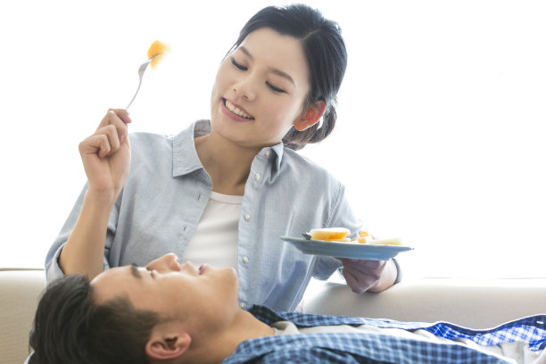 年轻的夫妇一起吃哈密瓜，丈夫躺在妻子的腿上——库存照片图片下载