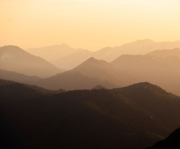 日落时被绿色森林覆盖的层次性山脉的鸟瞰图图片下载