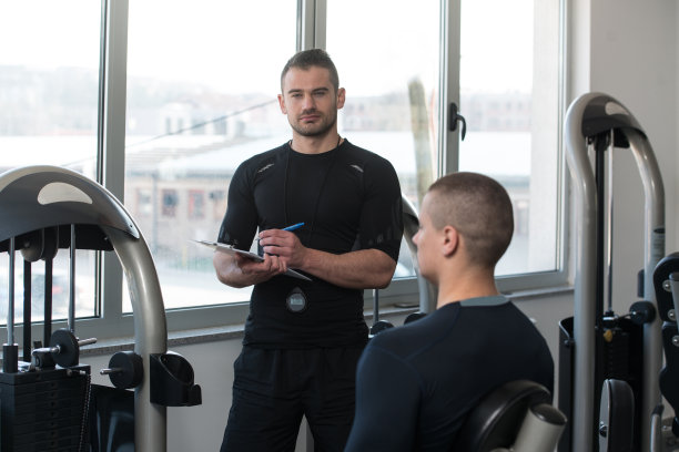 私人教练在男子锻炼腿部时做笔记图片下载