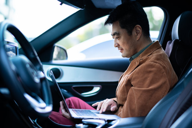 亚洲中年男子在车里用笔记本电脑图片下载