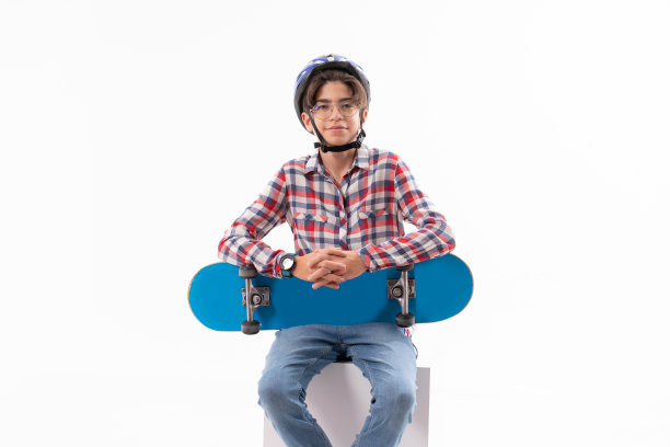 快乐的小男孩坐在和持有滑板在白色的背景图片下载