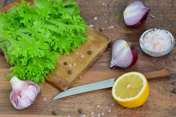青菜沙拉用刀放在切菜板上，红洋葱，大蒜和柠檬图片下载