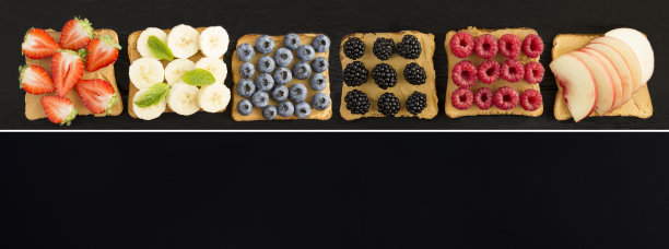 三明治拼贴画，黑色背景上有花生酱、水果和浆果。副本的空间。前视图。图片下载