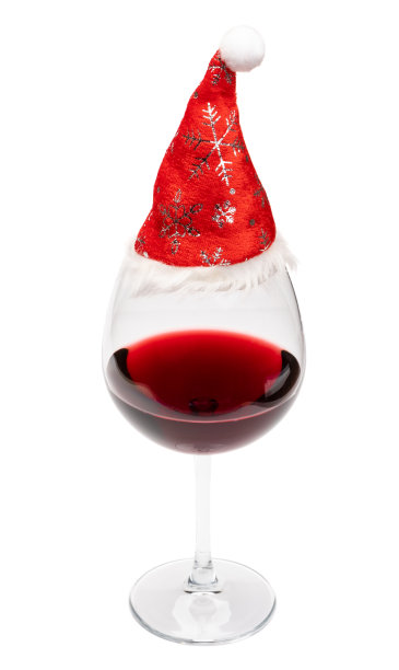 一杯圣诞红帽的葡萄酒，白色的帽子在上面图片下载