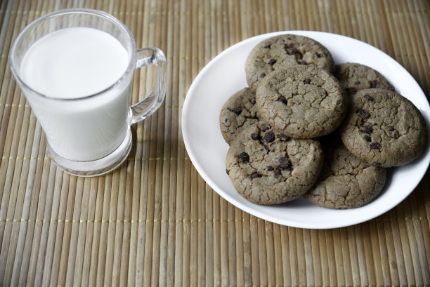 一杯牛奶放在木垫子上，配上燕麦饼干。下午午餐和饼干。加牛奶的甜饼干。图片下载