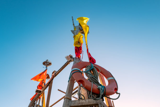 在摩托艇上看到的金属桅杆的抽象视图，显示救生圈、信号旗子和导航灯。图片下载