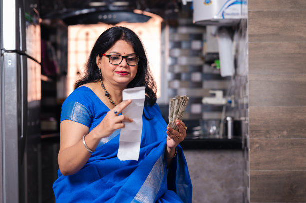 一个中年妇女坐在家里检查购物收据的镜头图片下载