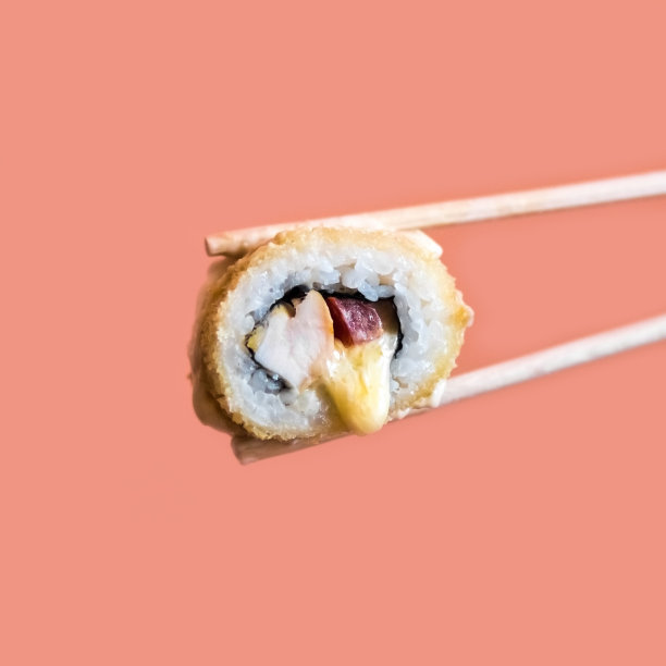 一只手拿着用木棍夹着的炸寿司卷和奶酪图片下载