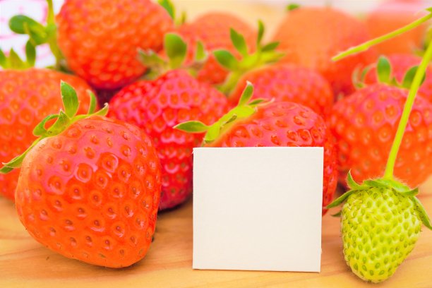 一张木桌上摆放着成熟的、仍是绿色的草莓，背景是一个评论框的模型图片下载