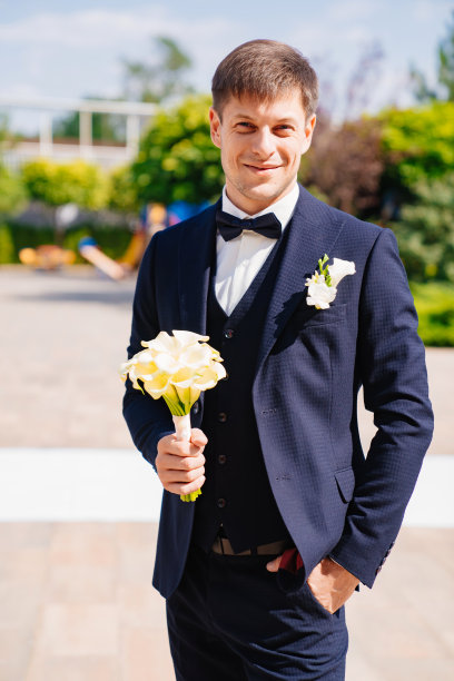 新郎穿着一套深蓝色的西装，上面有一个胸花和一束马蹄莲。图片下载