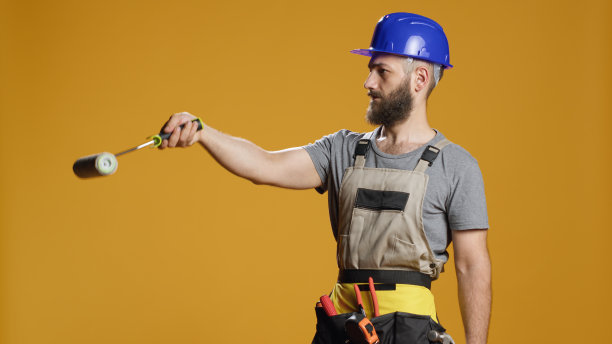 工业工人使用油漆刷辊油漆墙壁的肖像图片下载