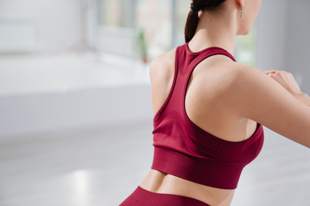 从后面看。一个穿着酒红色运动服的女人在锻炼。图片下载