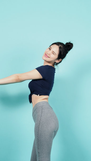 健身运动装女子微笑和姿势身体锻炼在相机孤立的蓝绿色背景。完美的身体运动女性放松后的训练。健康而坚定的人。运动健康与健康。图片下载