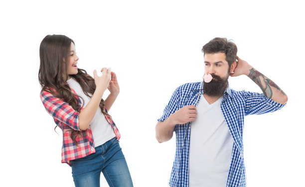 蓄着大胡子的父亲和照相亭的嘴唇摆出姿势，让用智能手机拍照的女孩拍照图片下载