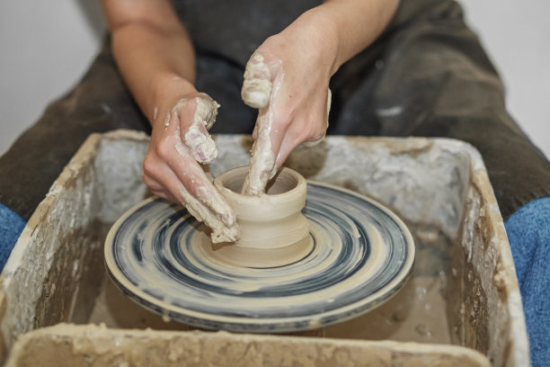 陶工姑娘在陶艺作坊的陶轮上工作，用陶土制作陶罐。艺术的概念图片下载