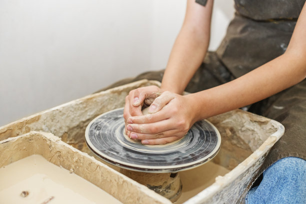 陶工姑娘在陶艺作坊的陶轮上工作，用陶土制作陶罐。艺术的概念图片下载