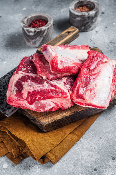 牛肉小牛肉排骨，生肉放在木砧板上。灰色的背景。俯视图图片下载