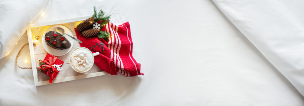 圣诞早餐放在床上，白色粉彩亚麻布。横幅。酒店的节日早餐。圣诞早餐装在白色的木托盘里。本空间图片下载