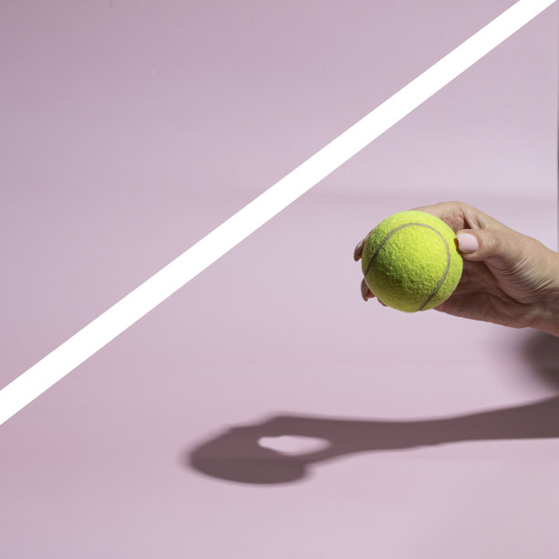 手握网球在粉红色背景与白线。图片下载