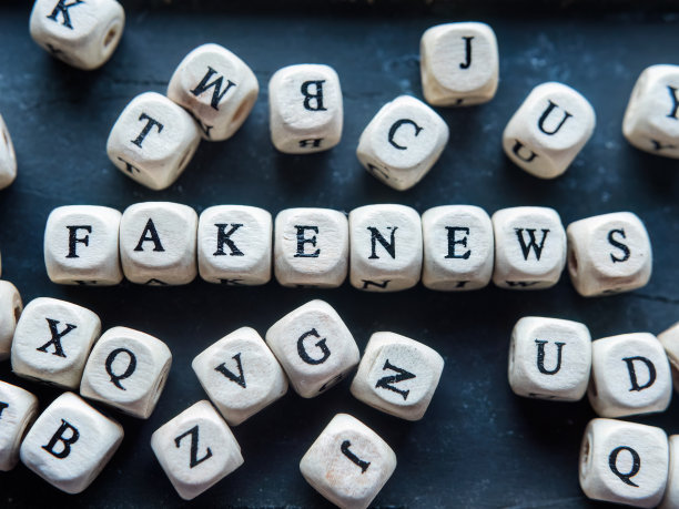 “假新闻”这个词是用字母珠子做成的，背景是黑色的木头图片下载