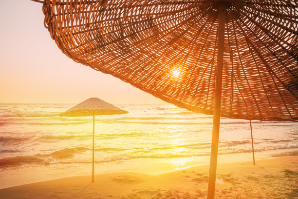 地中海度假胜地的柳条海滩伞。假期的概念。旅游公司的广告。田园般的热带沙滩上的沙滩伞。为休息，放松，假期，温泉，度假村设计的概念图片下载