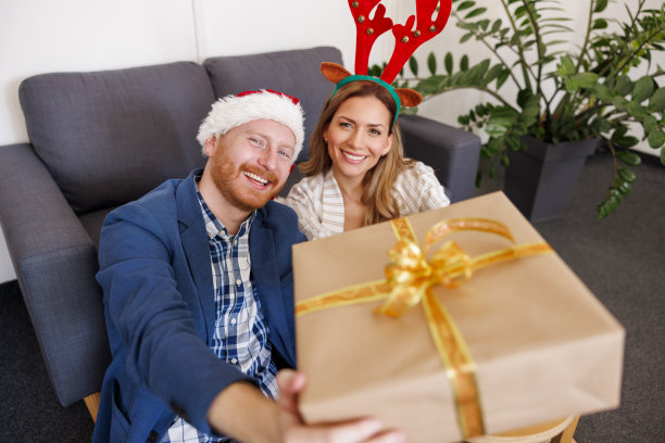 商务人士拿着包装精美的礼品盒在办公室庆祝圣诞节图片下载