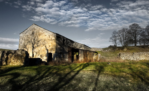 白天，在阴云密布的蓝天下，农村废弃的老建筑和木谷仓图片下载