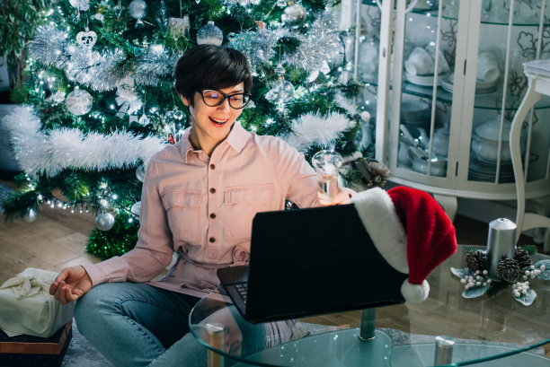 女人一边喝着香槟，一边与朋友或家人虚拟通话。在线庆祝圣诞节。网上新年欢迎会。笔记本电脑视频会议聊天。有选择性的重点。图片下载
