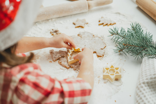 在白色的厨房里，小女孩模糊的双手在用面团切圣诞树姜饼饼干图片下载