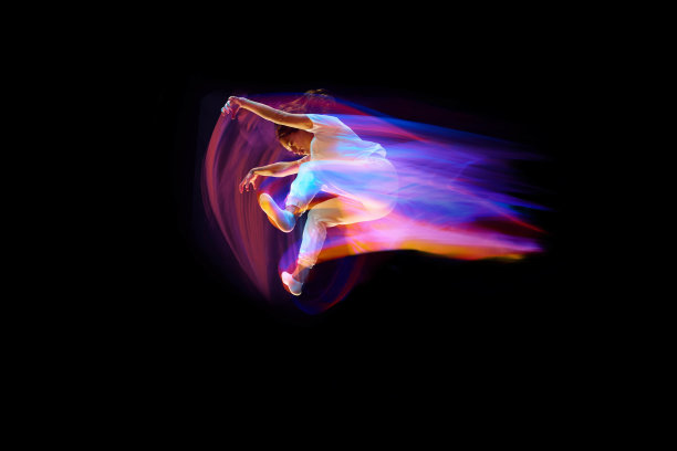 飞行的奇迹。年轻的运动舞者在白色的衣服悬浮，移动在混合霓虹灯的黑暗背景。创意艺术、抱负、音乐、时尚、舞蹈图片下载