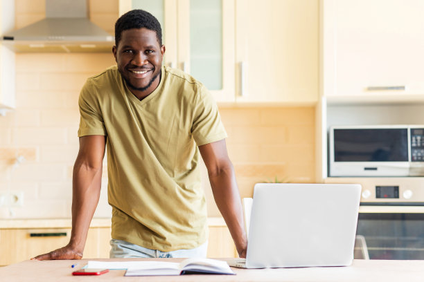 拉丁裔西班牙人在厨房用笔记本电脑和文件看起来很开心图片下载