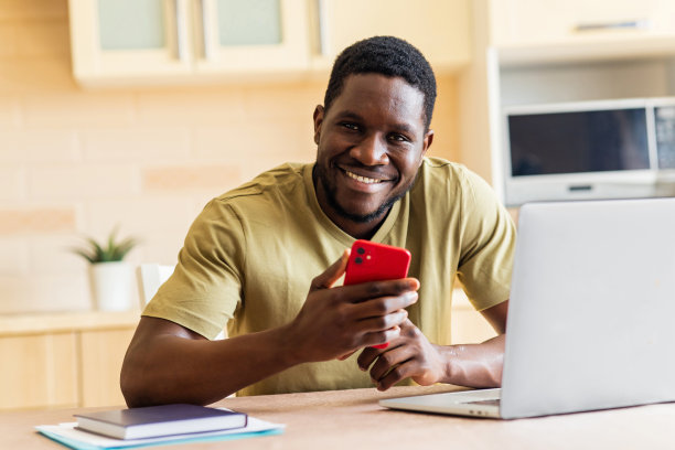 身穿米色t恤的非洲裔男子在家中用手机录制语音信息图片下载