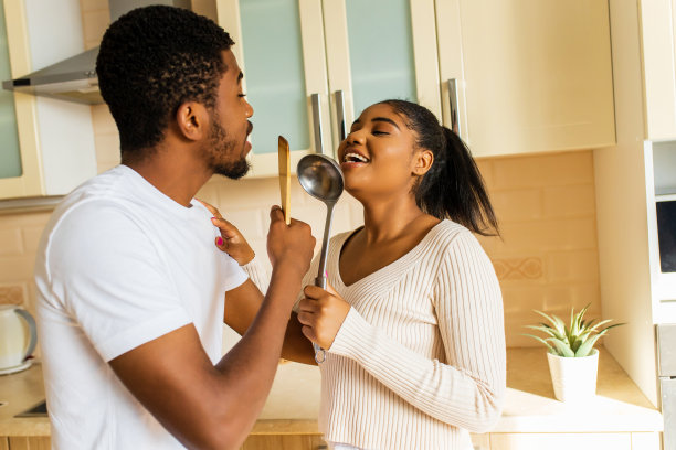 在厨房里，一对西班牙夫妇拿着勺子像麦克风一样一起唱歌图片下载