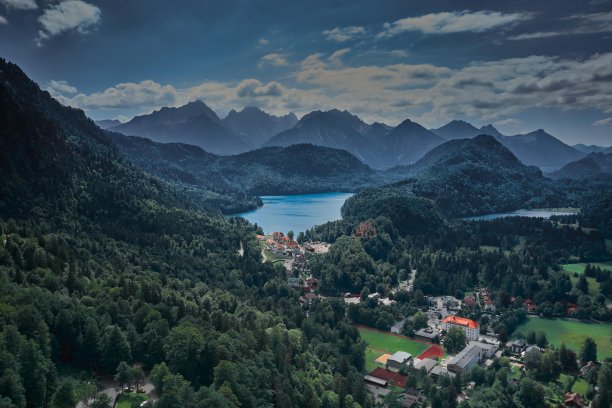 这是一个山谷的鸟瞰图，前面有一些树和房子，山谷有房子和小山的风景图片下载