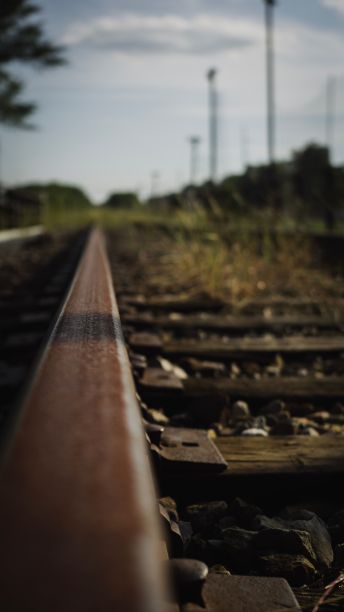 垂直拍摄的铁路与模糊的树木和灯杆的背景图片下载