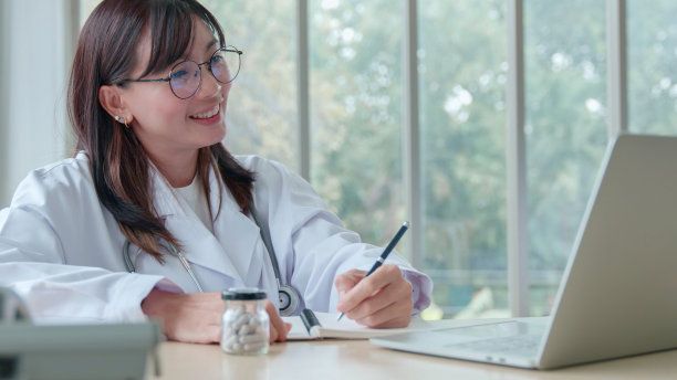 远程医疗咨询概念。微笑的亚洲女医生通过笔记本电脑上的视频通话在线咨询病人的疾病症状图片下载