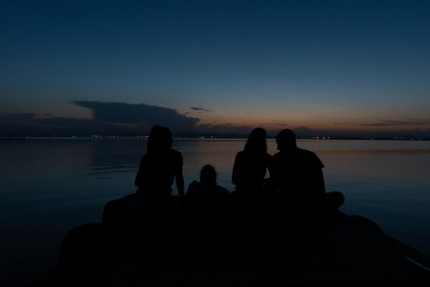 美丽的照片，四个朋友享受三个坐在和一个躺在泻湖码头上的美丽和浪漫的日落在瓦伦西亚，西班牙图片下载