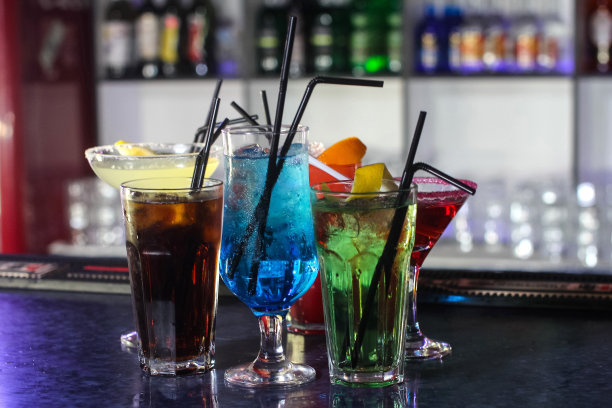 美味的创意明亮的鸡尾酒，酒精与吸管是在一个俱乐部或一个照明酒吧的桌子上图片下载