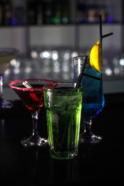 美味的创意明亮的鸡尾酒，酒精与吸管是在一个俱乐部或一个照明酒吧的桌子上图片下载