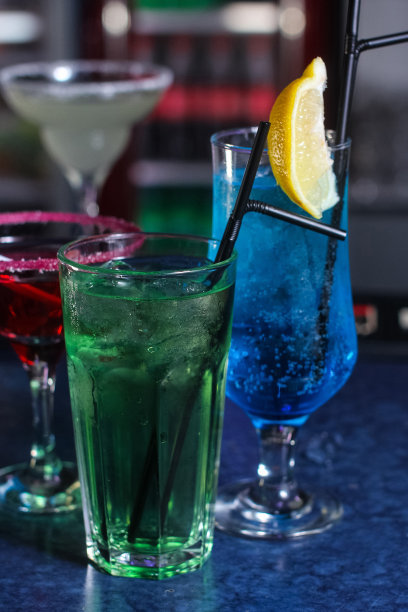 美味的创意明亮的鸡尾酒，酒精与吸管是在一个俱乐部或一个照明酒吧的桌子上图片下载