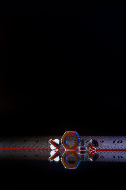 金属组成，不同尺寸镀铬螺母和一把金属尺。黑色背景。图片下载