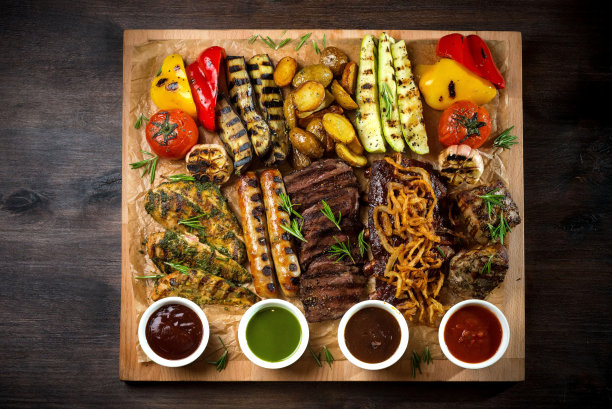 有烤开胃菜和酱汁的盘子。烤蔬菜和肉类零食:香肠、鸡柳、猪肉和牛排。图片下载