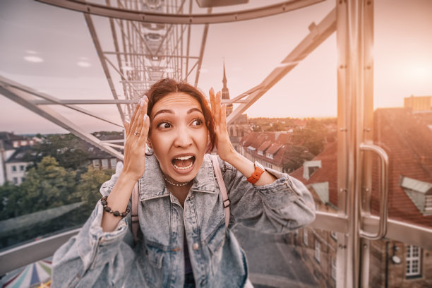 摩天轮上的恐高女孩正经历着恐高症的发作。过山车坏了，卡住了。心理恐惧症和心理问题图片下载