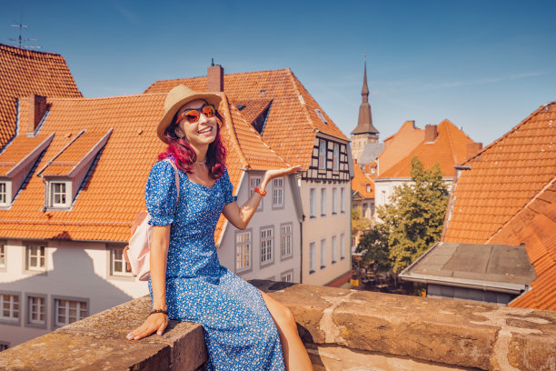 快乐的女人和背包旅游享受全景从橙色的屋顶的角度在德国奥斯纳布吕克的老城图片下载