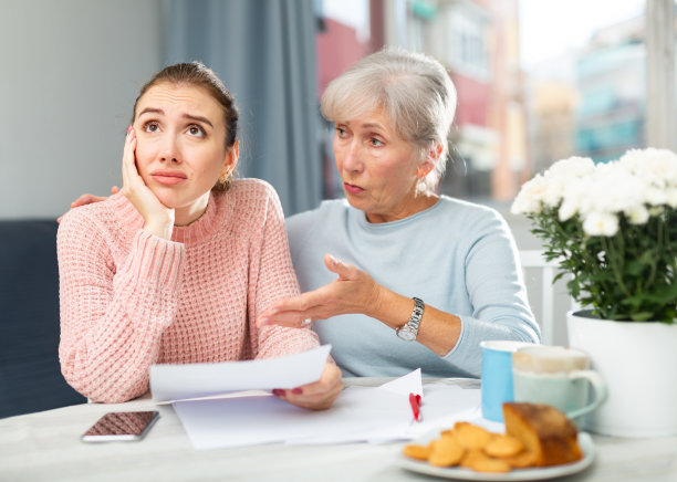 忧心忡忡的老妇人和成年的女儿在家里看文件图片下载