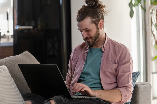 一个袖子上有纹身的年轻人正在笔记本电脑前专心工作。纹身的年轻自由职业者在一个新的创业项目中工作图片下载